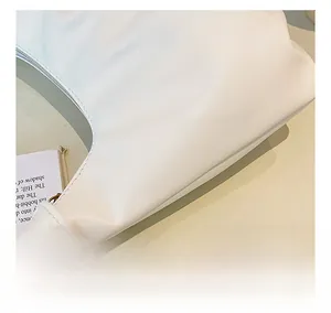 Detailed close-up of premium white leather texture and fine stitching on a pleated bag