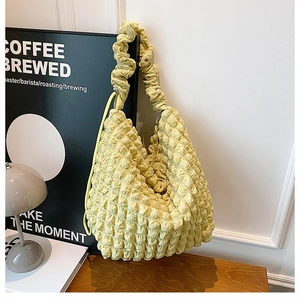 Close-up detail of soft popcorn texture and pleated shoulder strap on light yellow tote bag