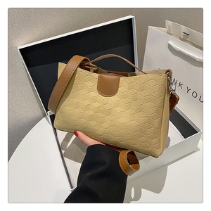 Detail view of apricot geometric embossed tote bag with brown leather handles and strap
