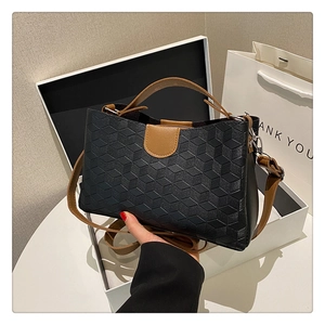 Detail of a black geometric embossed tote bag presented in an elegant gift box setup