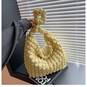 Macro detail of soft pleated texture and scrunchie handle on yellow cloud bag