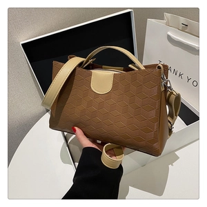 Macro view of geometric quilted pattern on brown leather tote bag with contrast strap