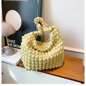 Detail of light yellow popcorn fabric texture on a soft pleated cloud shoulder bag