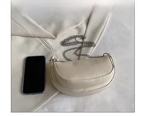 Beige saddle bag size comparison with a smartphone and silver chain strap detail