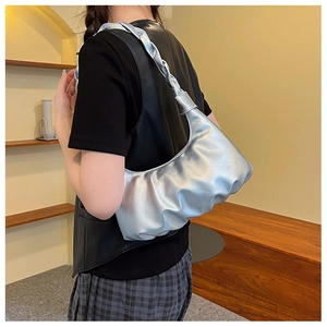 Silver pleated cloud bag with braided strap shown on model in a stylish indoor setting