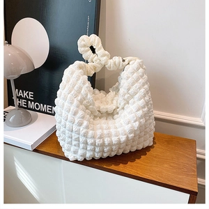 Detail of white popcorn fabric handbag with textured surface and knotted handle design