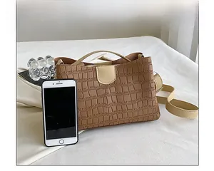 Vue détaillée de la texture crocodile marron et du fermoir magnétique beige du sac en PU