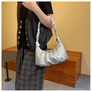 Detail of silver pleated cloud bag featuring a glossy braided handle for shoulder carry