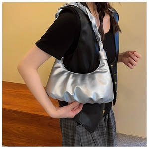 Detail of silver metallic cloud bag with chunky woven strap worn by a female model