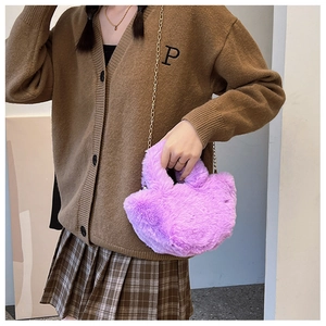 Detail einer lila flauschigen Herz-Tasche mit Goldkette an einem Model-Outfit getragen