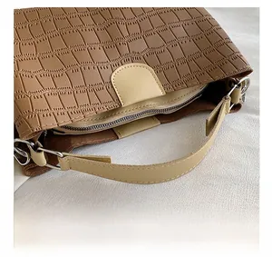 Gros plan sur le cuir marron motif crocodile avec poignée crème et détails de couture