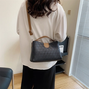 Fashionable black geometric textured shoulder bag with brown straps on model's back