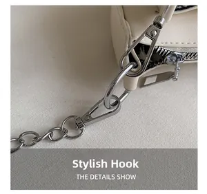 Detailed close-up of detachable silver metal chain link and lobster clasp on beige bag