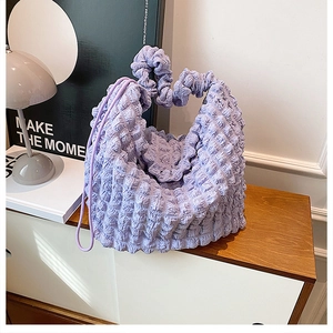 Close-up of soft lilac popcorn fabric texture and pleated handle on cloud shoulder bag