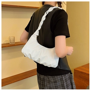 Detailed view of white pleated cloud bag with a unique woven strap on a model shoulder