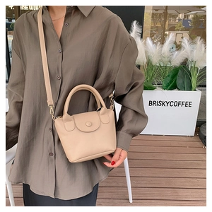 Mini sac à main en cuir grainé sur un modèle dans un cadre de café en plein air