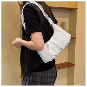 Detail view of the white ruched cloud bag with wide shoulder strap on model