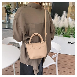 Détail d'un mini sac beige en cuir à grain litchi avec rabat à bouton rond et bandoulière