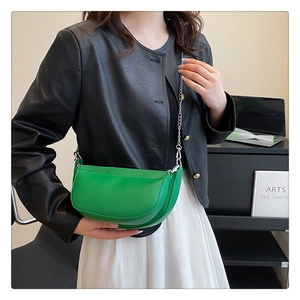 Close-up of vibrant green semi-circle saddle bag with silver chain strap on model