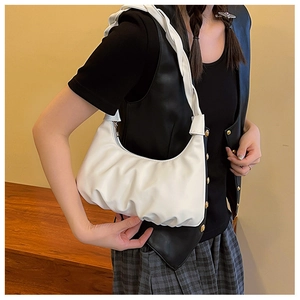 Detailed close-up of white ruched cloud bag with wide shoulder strap on a model