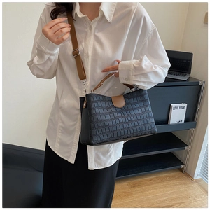 Détail du sac noir motif crocodile avec bandoulières marron et boucle contrastée