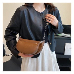 Close-up of brown semi-circle PU leather saddle bag with silver metal chain strap