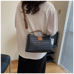 Vue détaillée du sac noir texture crocodile avec bandoulières marron sur mannequin