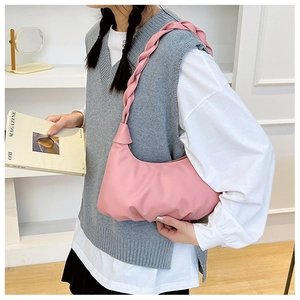 Detailed shot of pink pleated cloud bag with wide woven strap on a female model