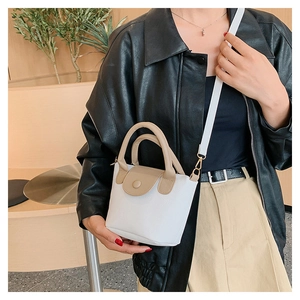Détail du mini sac seau montrant le cuir grainé et la bandoulière amovible