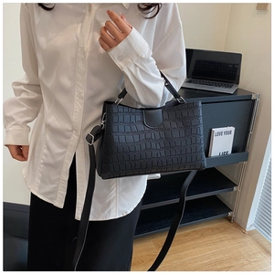 Détail du sac à main noir motif crocodile avec bandoulière élégante pour femme