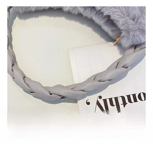Détail du sac à main en fausse fourrure grise avec poignée tissée et fermeture dorée