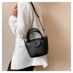 Détail du mini sac à main en cuir grainé noir porté avec une veste de blazer blanche chic
