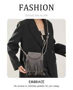 Détail du sac à bandoulière gris à franges sur le blazer noir du mannequin