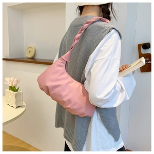 Detail view of pink ruched cloud bag with woven handle worn as a shoulder bag