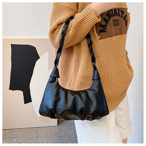 Fashionable black pleated cloud bag with unique woven shoulder strap worn by a model