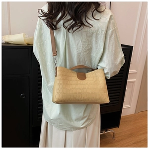 Détail de la texture cuir croco beige et de la bandoulière marron du sac à bandoulière