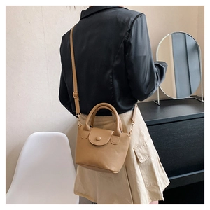 Vue détaillée d'un sac à main beige grainé avec rabat porté par un mannequin