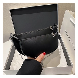 Detail of minimalist black leather half-moon bag with double silver zipper and chain strap