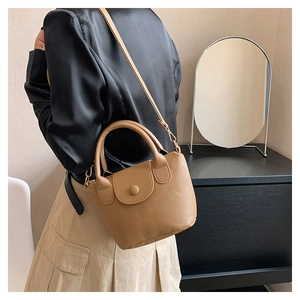 Détail du sac seau en cuir camel avec motif litchi, poignée et bandoulière fine