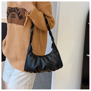 Detail of black pleated cloud bag featuring a thick braided shoulder strap texture