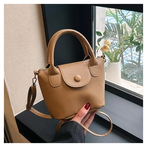 Détail d'un mini sac à main en cuir marron à motif litchi avec poignées et rabat boutonné