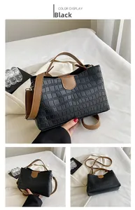 Détail du sac à main noir motif crocodile avec poignée et bandoulière marron contrastant