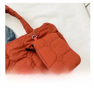 Detail of brick red quilted nylon mini pouch attachment with hexagonal stitching and metal chain