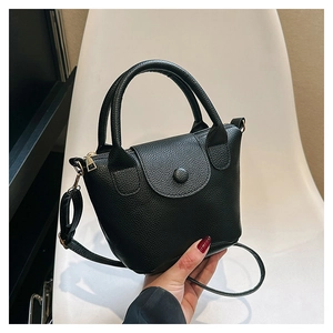 Détail du mini sac à main en cuir grainé noir avec ferrures dorées et poignée supérieure