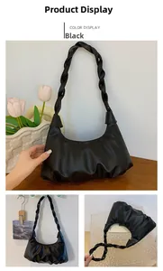 Detail of black pleated hobo bag with woven strap on a wooden table with tulips