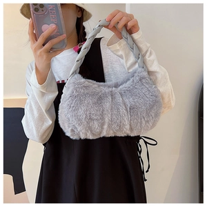 Détail du sac à main en fausse fourrure grise avec anse tressée porté par un mannequin chic