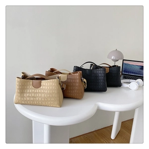 Vue à plat de quatre sacs fourre-tout texturés avec de longues bretelles sur un bureau