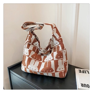 Detail view of woven knit shoulder bag with brown rabbit pattern and checkered texture