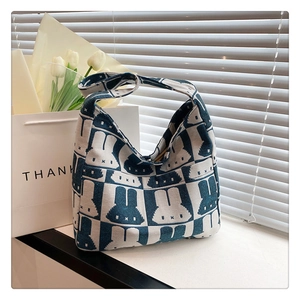 Detail of blue knitted checkerboard bag featuring cartoon rabbit patterns on a sunny windowsill