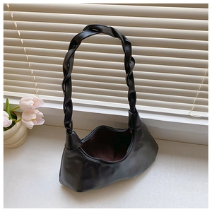 Detail of a black crescent shoulder bag with a unique braided leather handle design